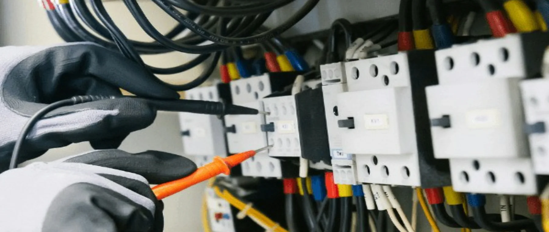 An electrician testing wiring inside an industrial control panel