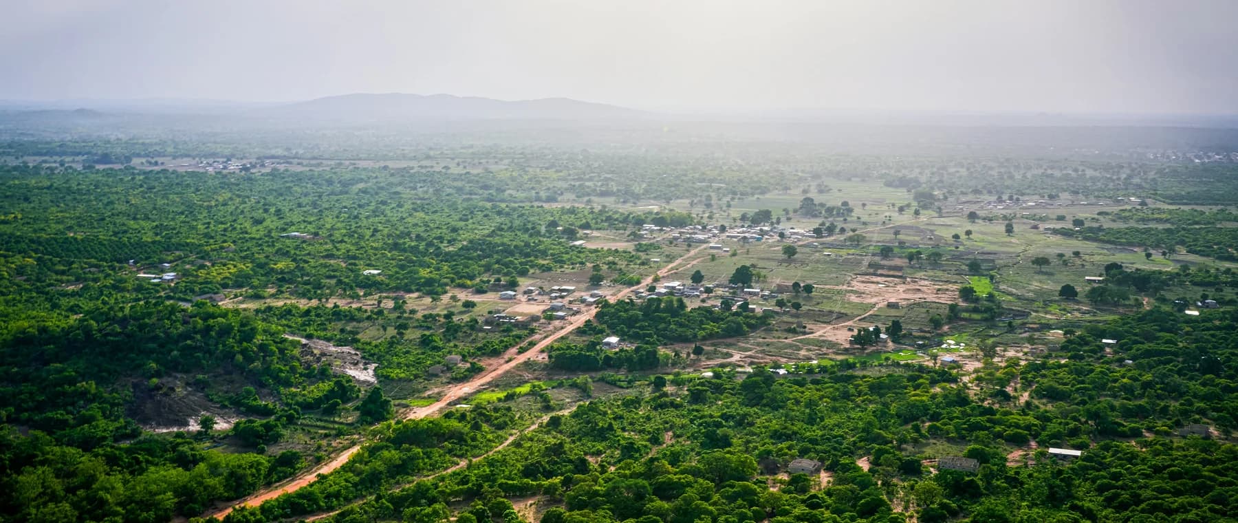 Expansive landscape with a dirt road and scattered buildings